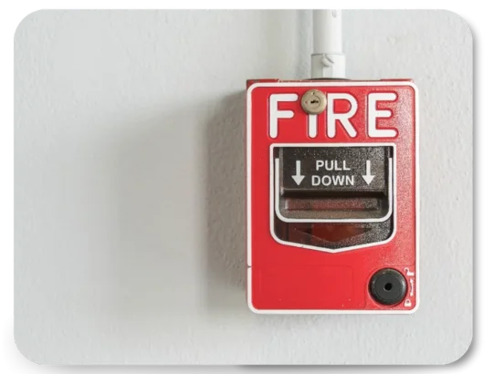 Red fire alarm pull station with "PULL DOWN" instructions mounted on a white wall.